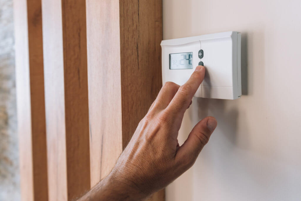 male-hand-pushing-the-button-of-home-heating-and-c-NOv-B3.2-1-1024x683
